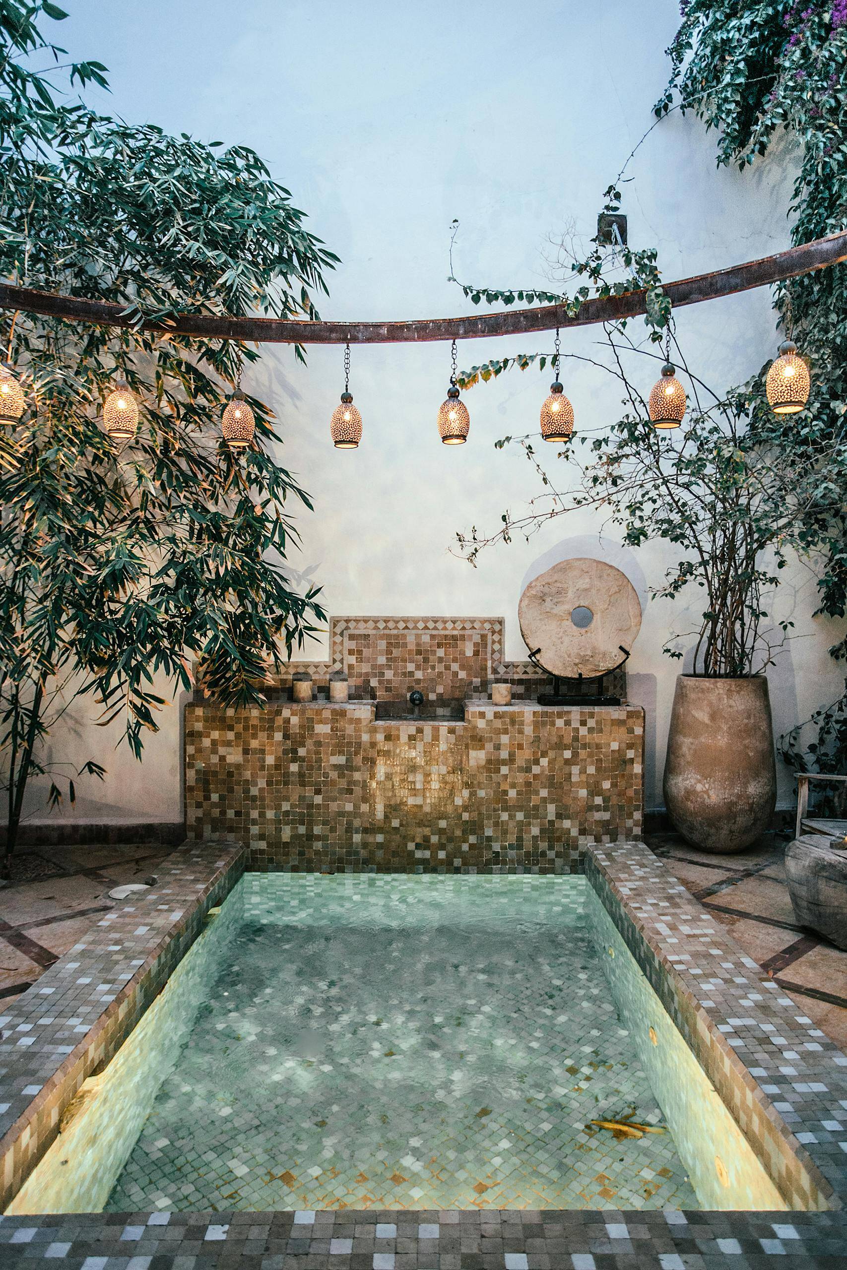 Interior of vintage patio decorated with plants in pots and green exotic trees with pool decorated with ornaments in summer time