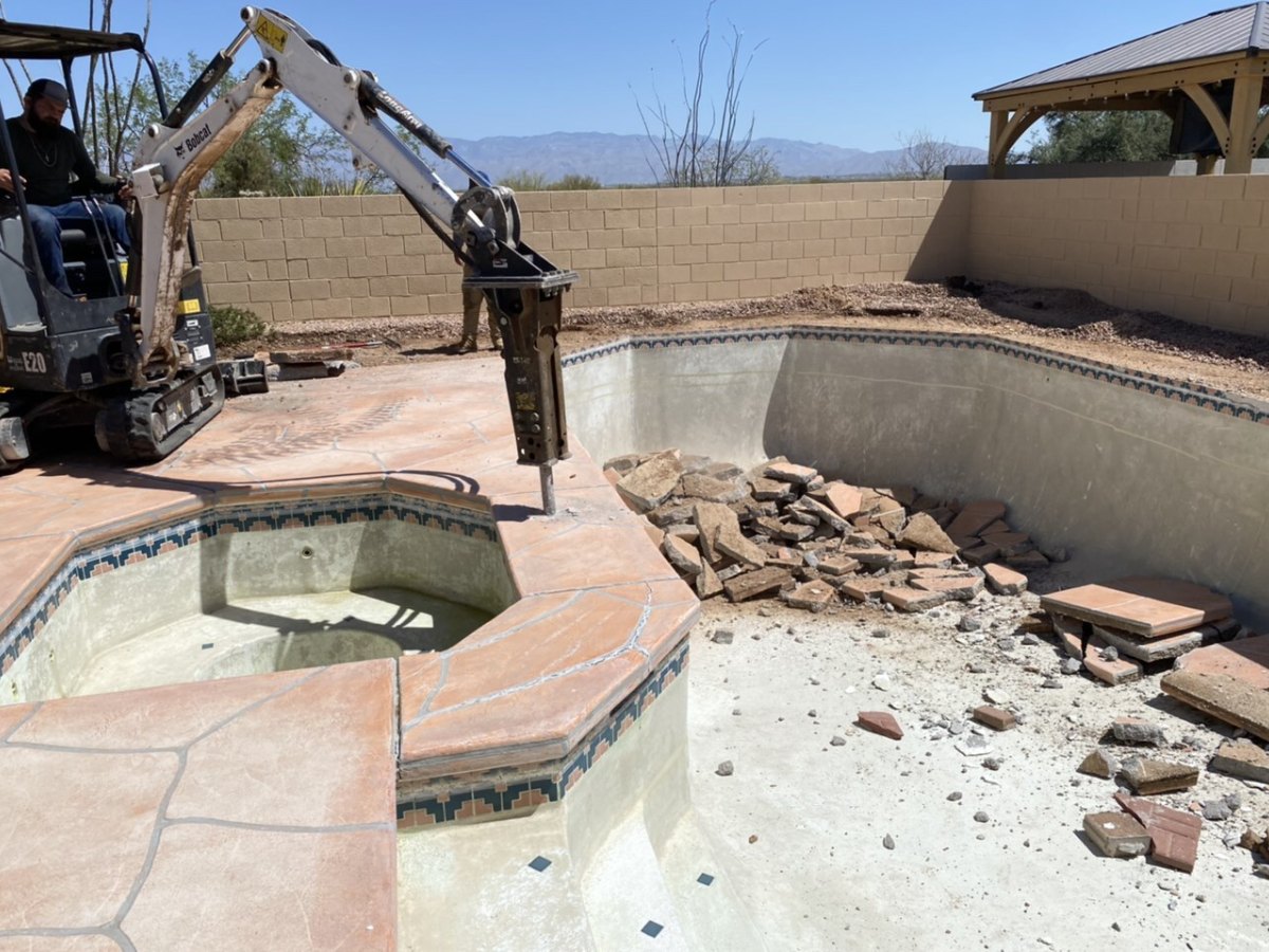 Mini excavator breaking out a spa bond beam and pool deck