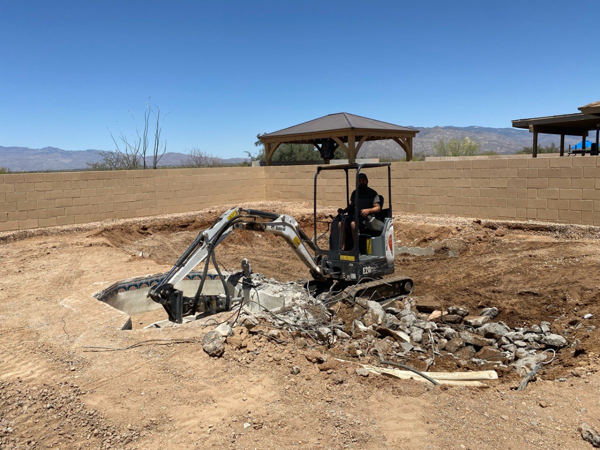 Mini excavator backfilling a pool